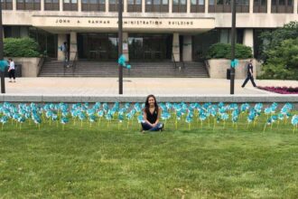 Former gymnast kaylee lorincz sits outside the hannah administration building on michigan state university campus in 2018 surrounded by teal pinwheels placed to represent support for survivors of ex-msu and olympic doctor larry nassar.