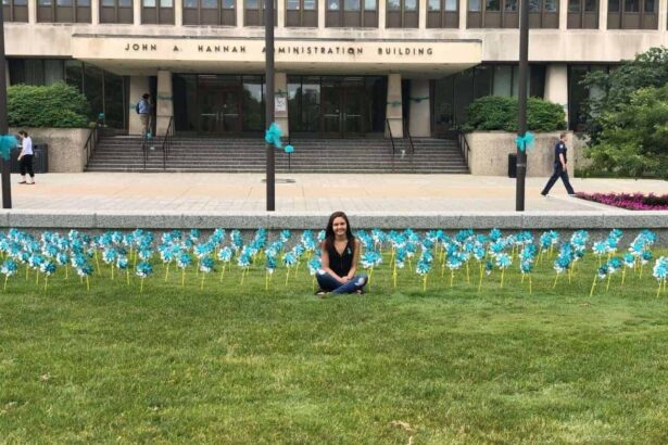 Former gymnast kaylee lorincz sits outside the hannah administration building on michigan state university campus in 2018 surrounded by teal pinwheels placed to represent support for survivors of ex-msu and olympic doctor larry nassar.