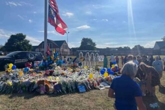 Community members and students gather around a flagpole on the apalachee high school campus near winder, georgia, on sept. 8, leaving flowers and messages to memorialize the four people killed in the sept. 4 shooting there.