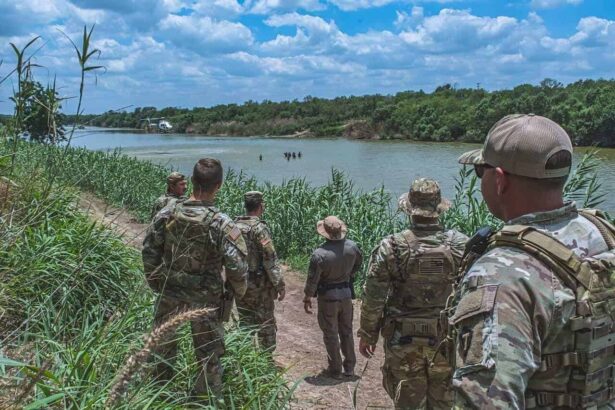 Members of the texas national guard watch a border patrol helicopter hover above a group of civilians wading in the rio grande along the texas-mexico border during operation lone star.