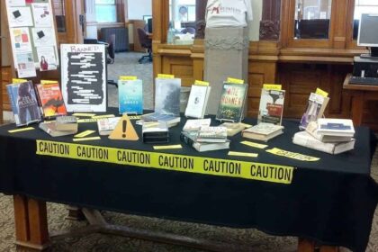 A banned book display in a library with police caution tape around the table