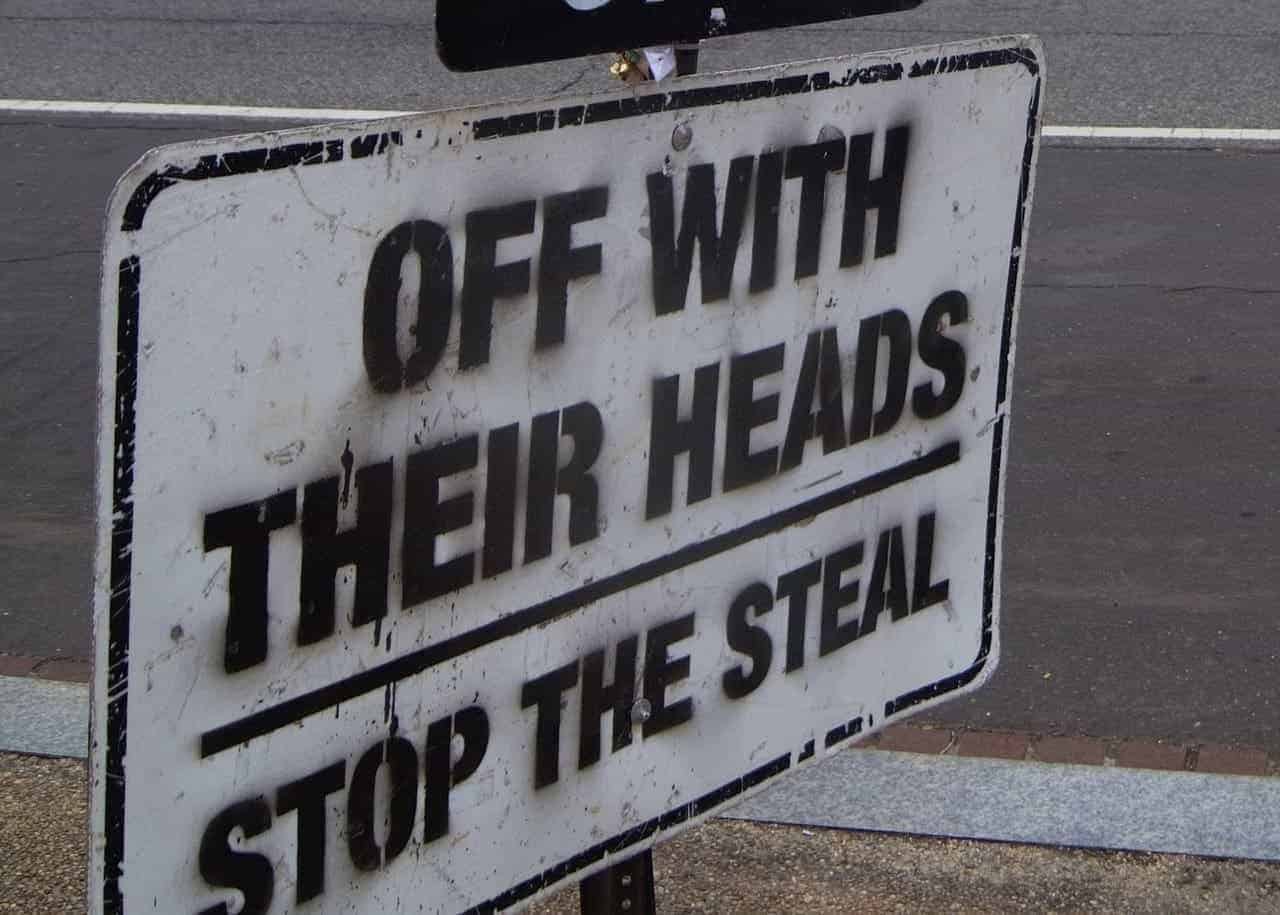 A sign that says, “off with their heads, stop the steal”