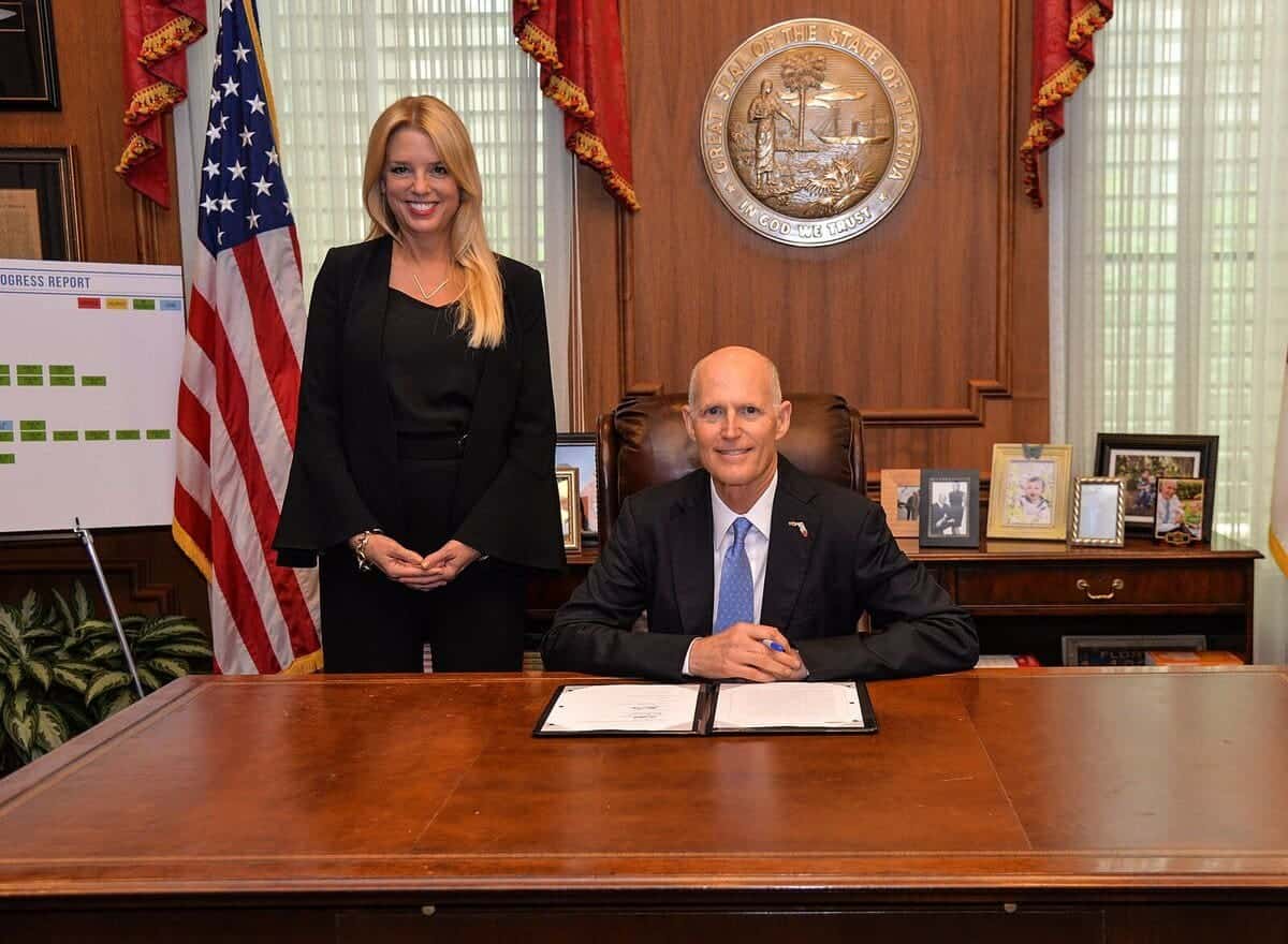 Pam bondi stands beside governor rick scott during a bill signing.