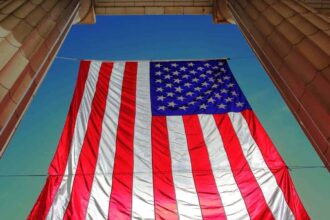 Underneath view of an american flag hanging with a blue sky in the background