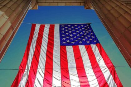 Underneath view of an american flag hanging with a blue sky in the background