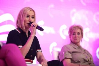 Pastor paula white speaks on stage with linda mcmahon.