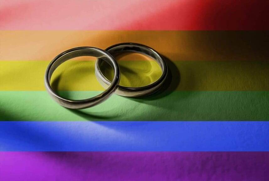 Anti-lqbtq+ policies harm the health of all americans wedding rings on a rainbow flag background