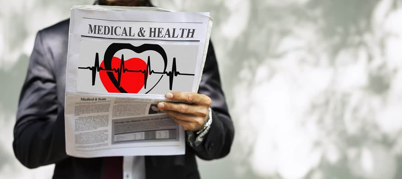 Man in suit holding a newspaper with medical & health headline