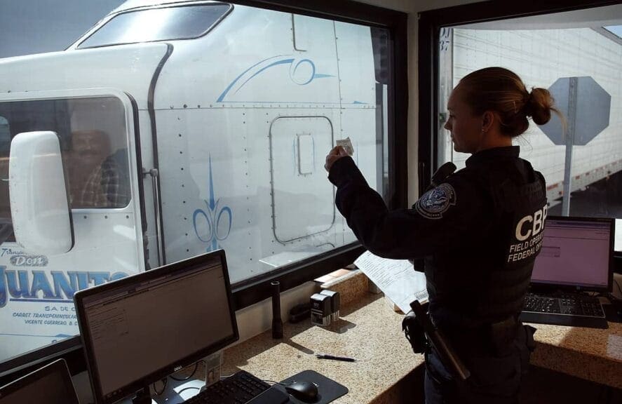 A U.S. Customs and Border Protection officer checks the identification of truck driver as he passes through the U.S. checkpoint of the Cargo Pre-Inspection at the Otay Mesa, Calif., port of entry, June 22, 2016. On any given day, several hundred trucks line up on the Mexican side of the border to deliver imports ultimately awaiting the process of screening by customs officers.