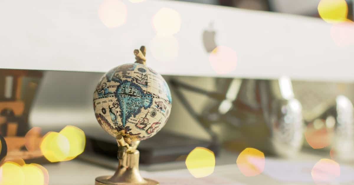 Close-up of a miniature globe on an office desk with a bokeh light effect, creating a dreamy atmosphere.