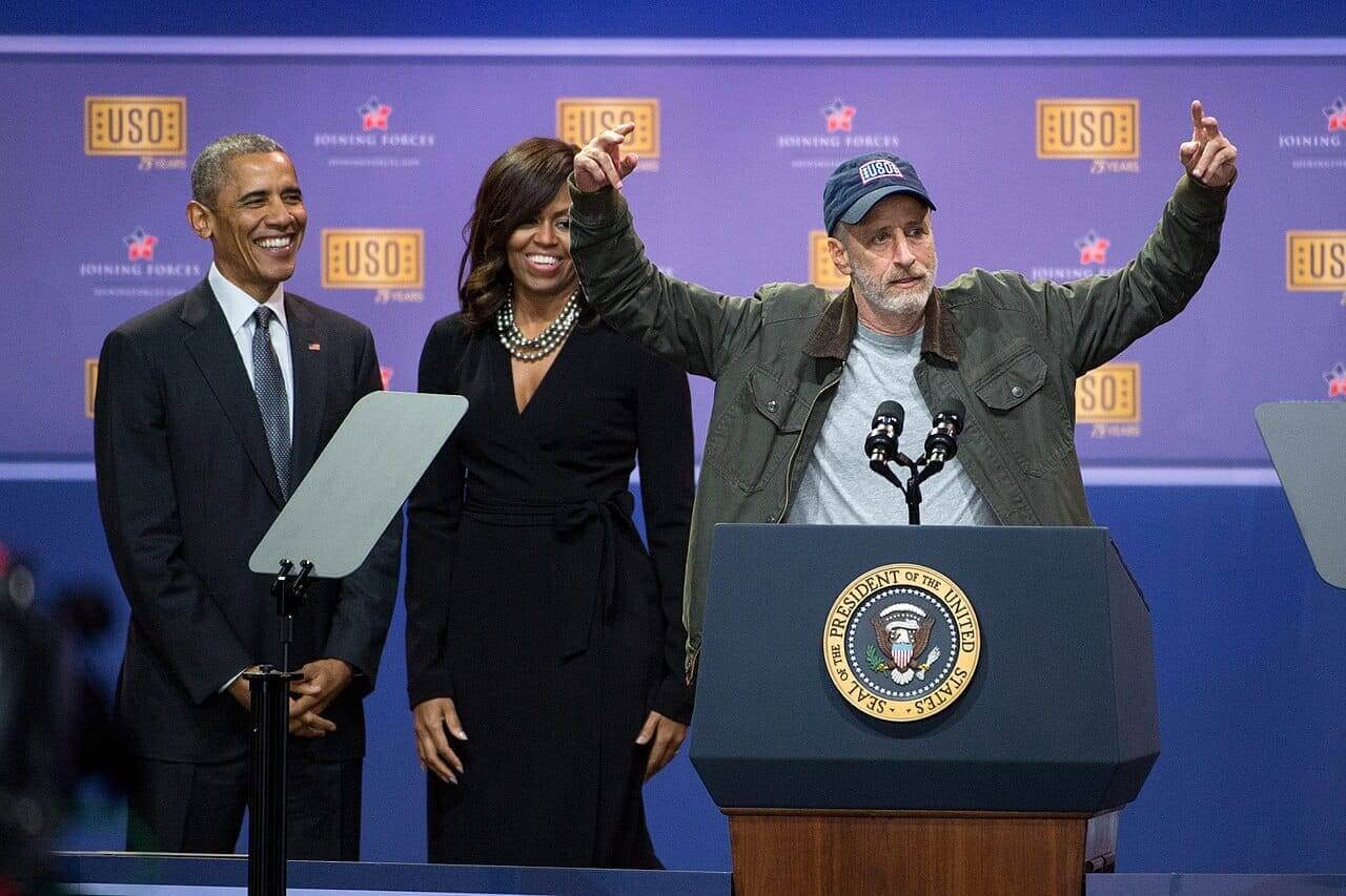 Jon stewart on stage with the obamas