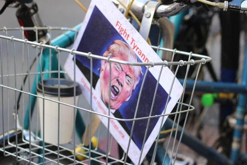 Our president is a fascist a fight tyranny sign with a photo of donald trump in the basket on a bicycle