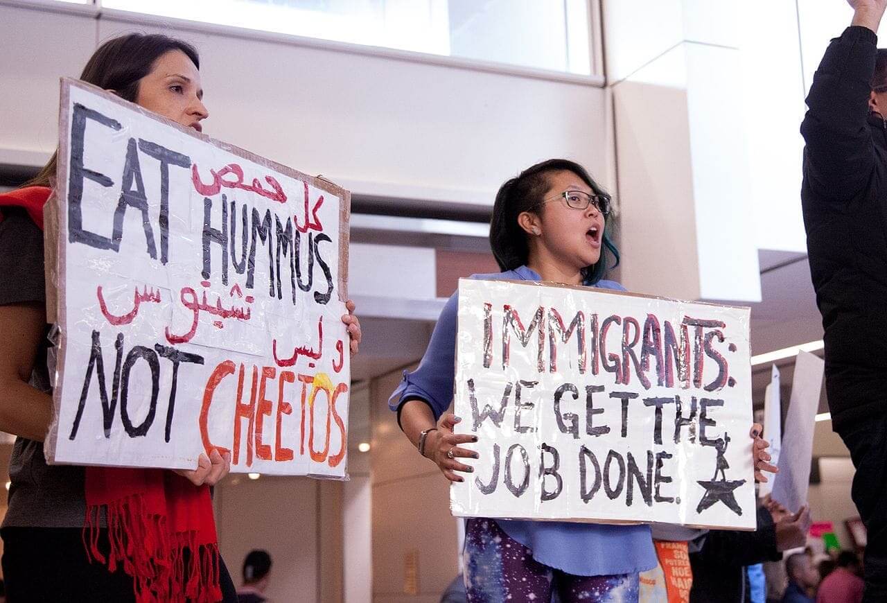 Immigrants protest with a sign that says immigrants get the job done