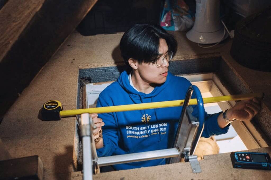 Community energy a man at the top of a ladder through an opening to the attic