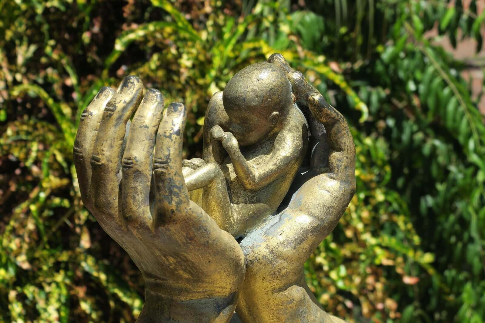 Sculpture of a baby between 2 hands
