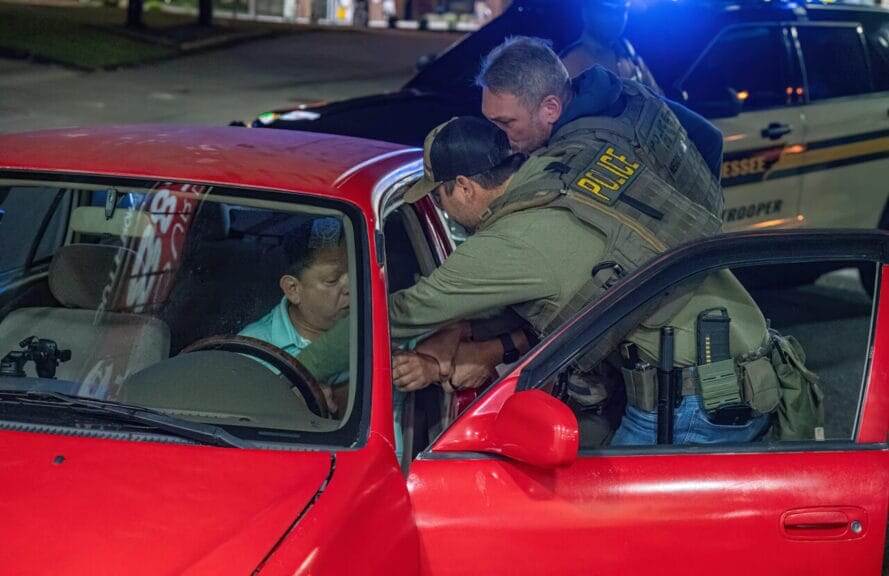 Agents from the Immigration and Customs Enforcement Agency reach into a car to pull a driver out on May 9, 2025 in Nashville.