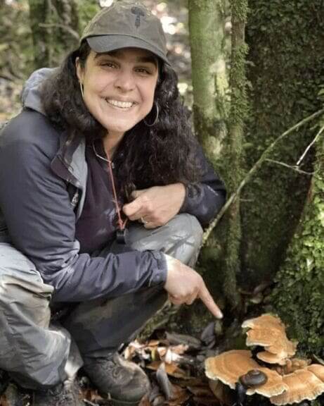 woman pointing to mushrooms in woods Woman in nature pointing to mushrooms.