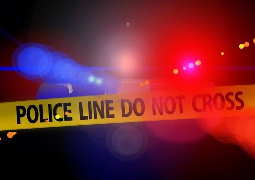 Violent crime. Blurry police car lights in the background behind yellow crime tape