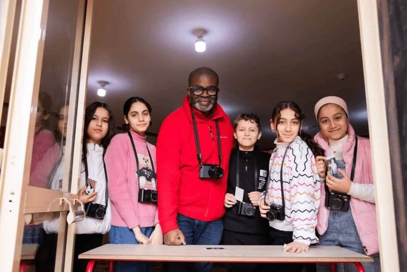 Man and group of gazan refugee children with cameras around their necks.