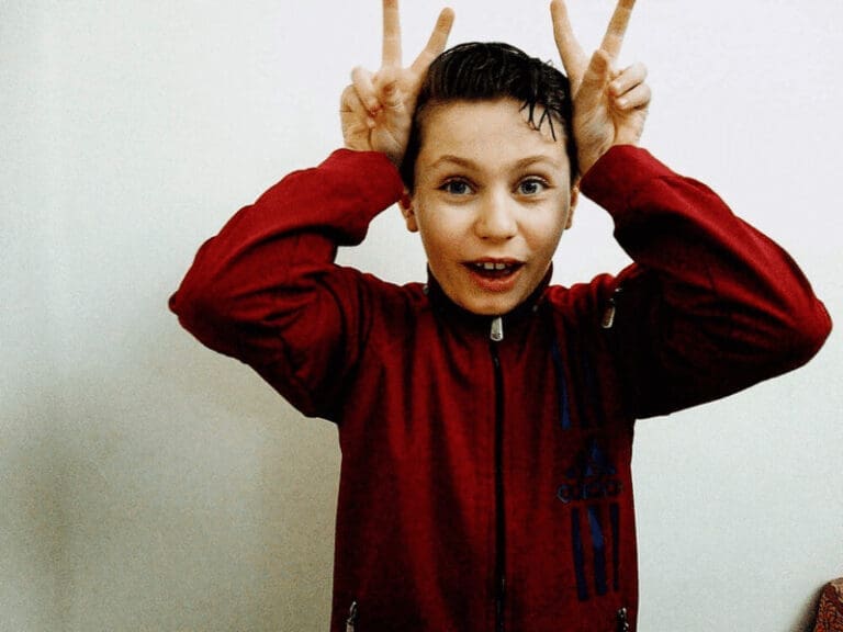 Young boy making bunny ear gestures on his head with his hands.