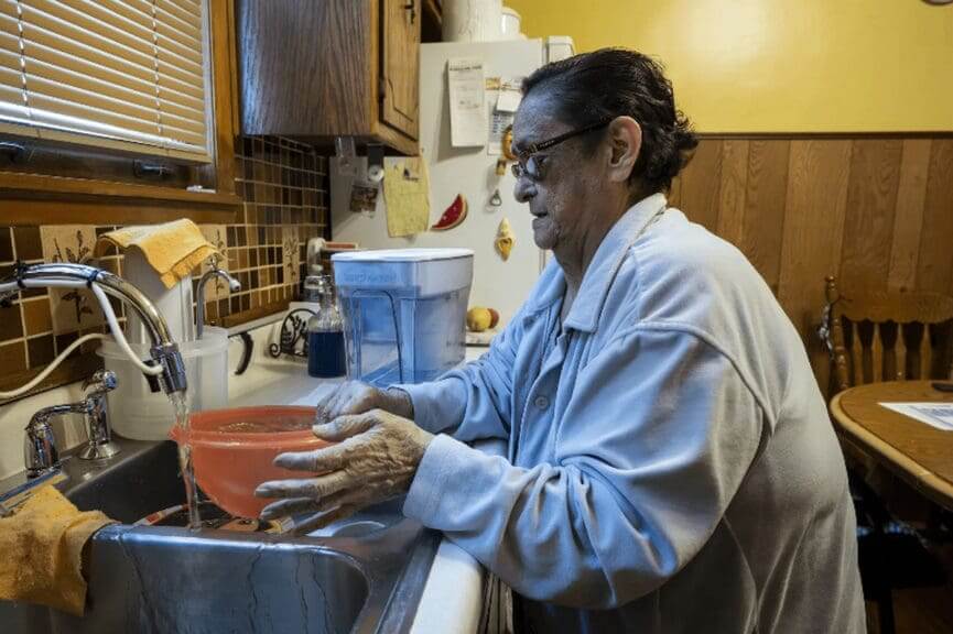 Woman washing dishes who didn't know about lead pipes.