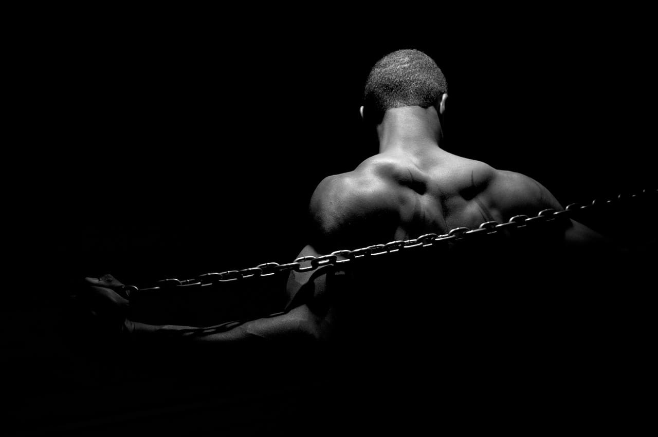 Black man in chains, black background, black and white photo