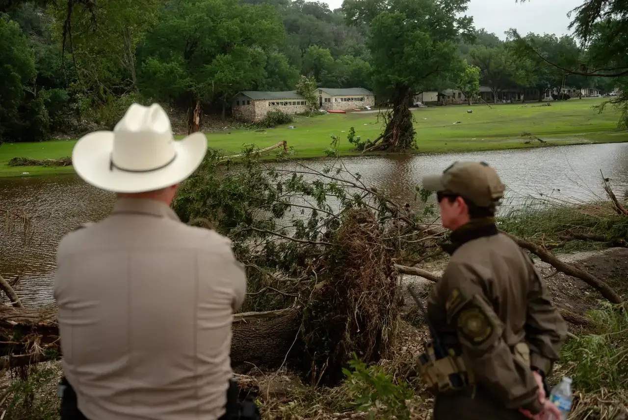 Police officers on the riverbank across from camp mystic in texas after flood