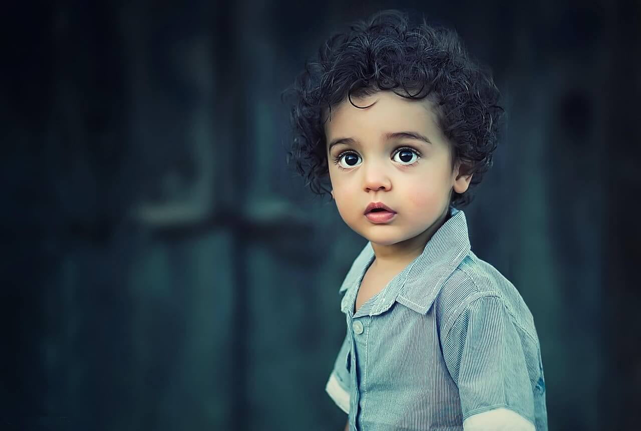Immigrant children little boy with dark, curly hair and big eyes