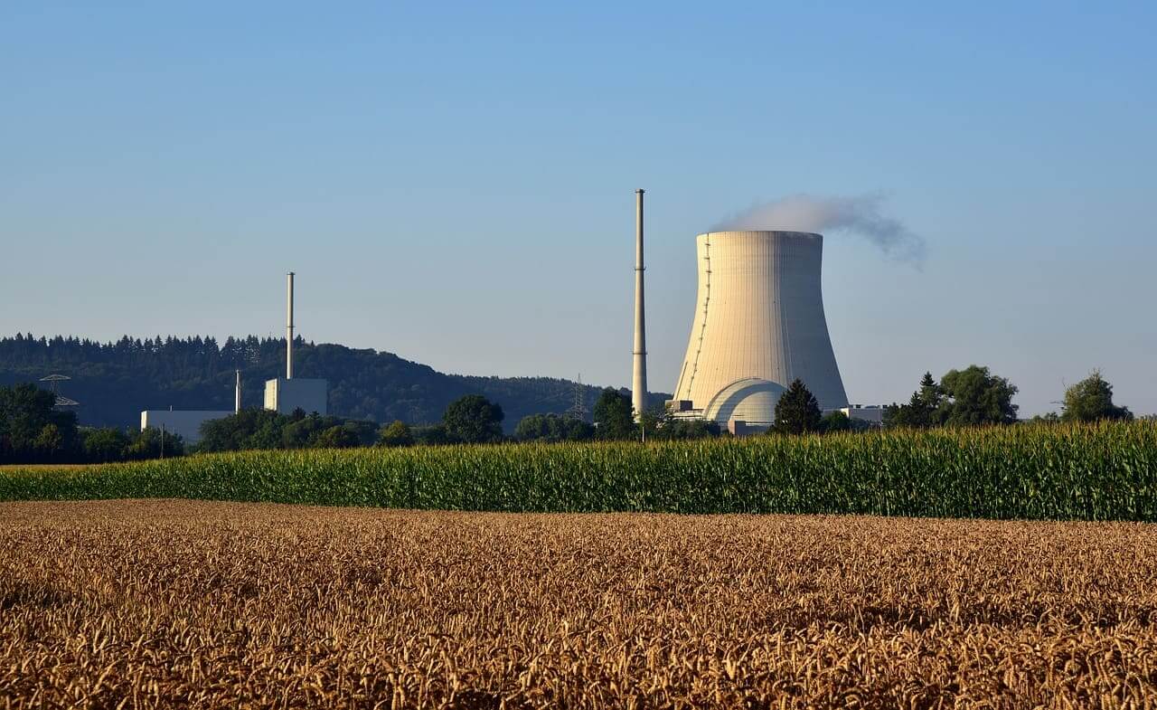 A functional nuclear power plant seen across a field in the country.