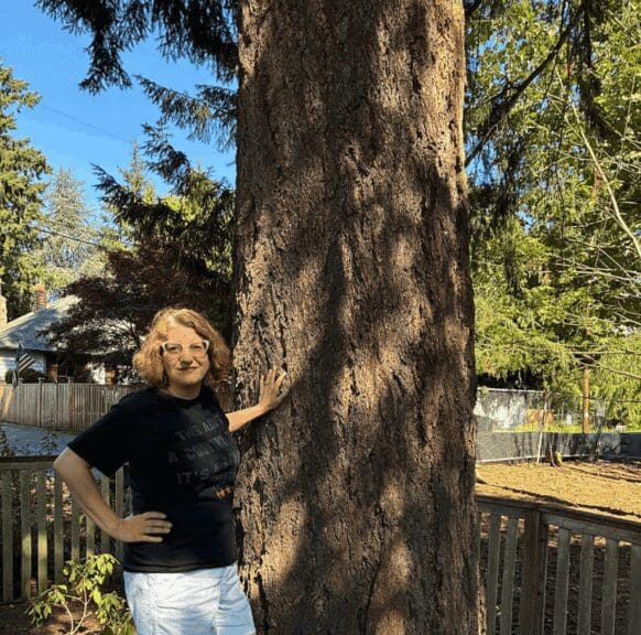 Homeowner standing beside a tree.
