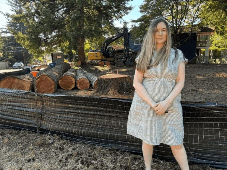 Woman standing beside trees that were cut down