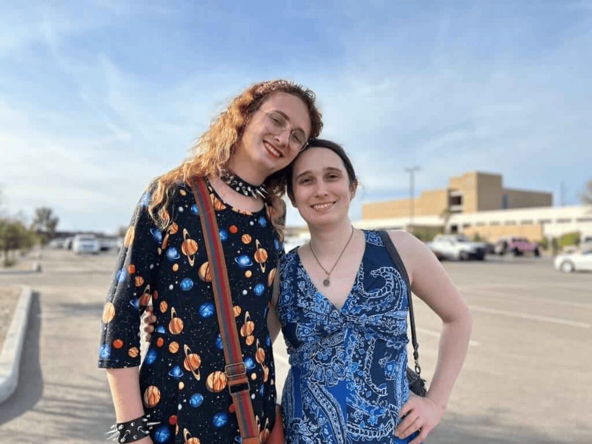 Two women standing next to each other with arms around shoulders