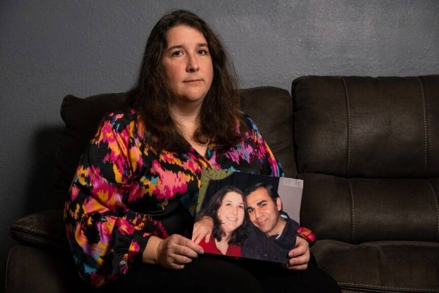 Woman holding photo of her with her husband who was arrested by ICE