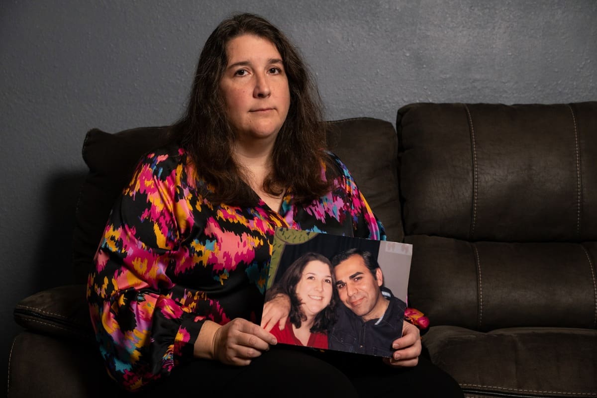 Woman holding photo of her with her husband who was arrested by ice