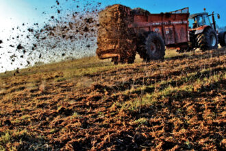 Tractor dropping manure in a field on a farm