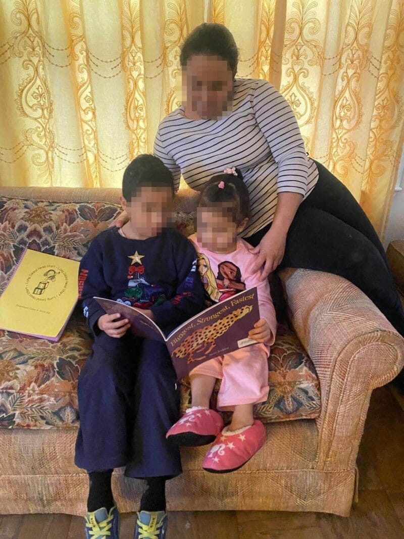 Mother an two children on a couch reading books. Honduran family