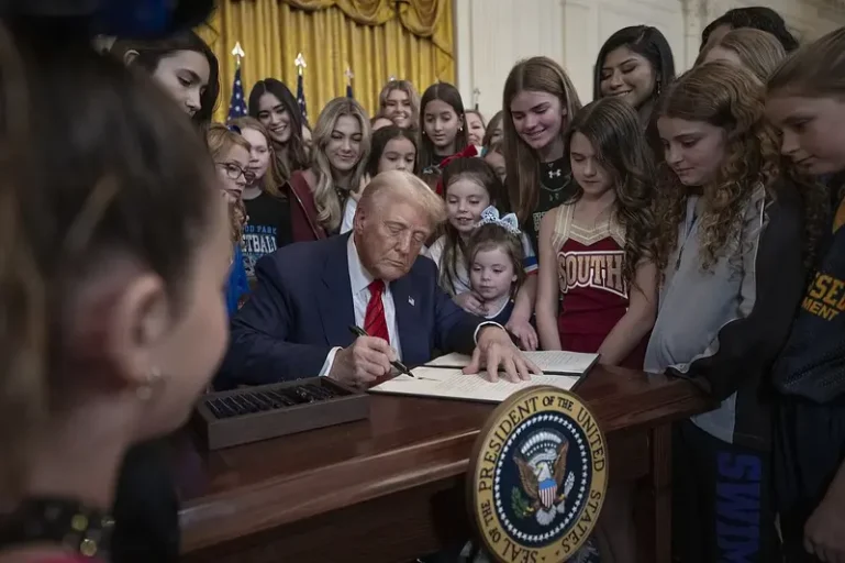 Trump signing an order with kids around him