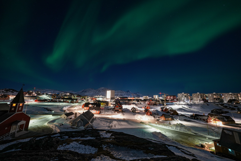 The nuuk, greenland skyline at night under the aurora borealis.