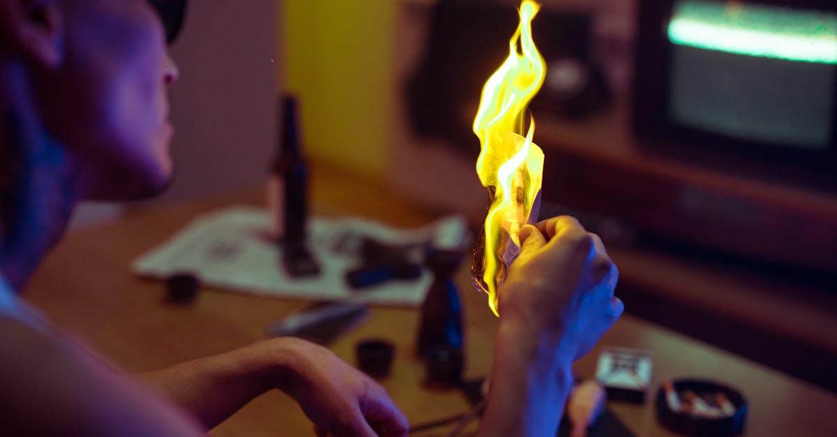 A person holding a burning piece of paper indoors, creating a dramatic and moody atmosphere. Project 2025 is burning down the country.