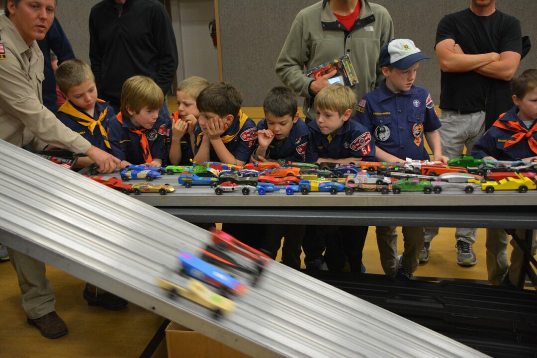 Boy scouts doing a race car project with troop leader