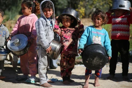 Children in Gaza wait in a line for food. Violence in Gaza continues