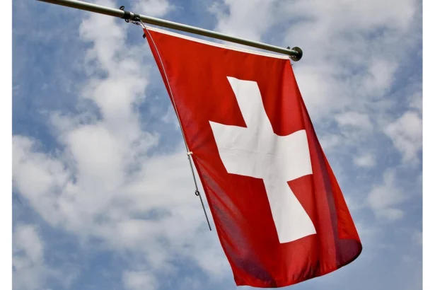Flag of switzerland against a blue, cloudy sky