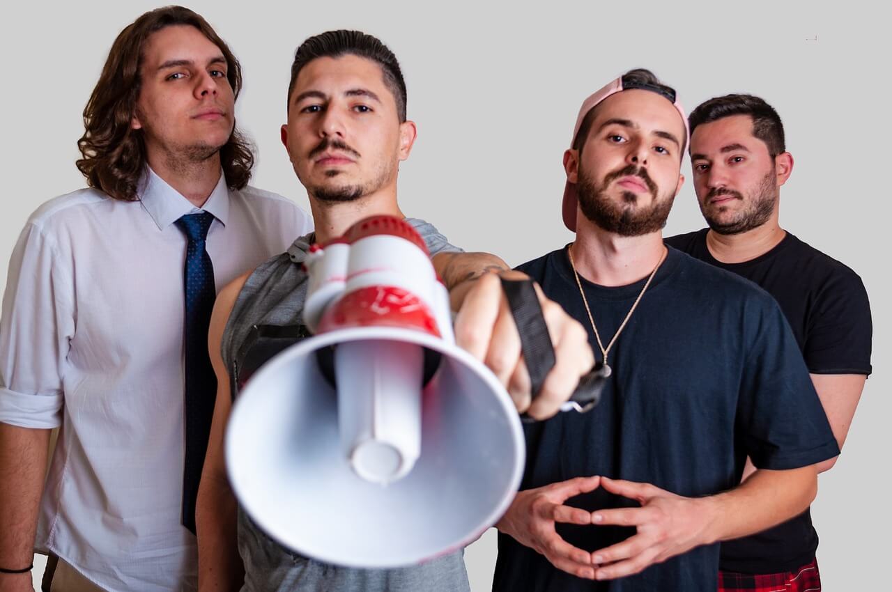 4 men in a group with one holding a bullhorn