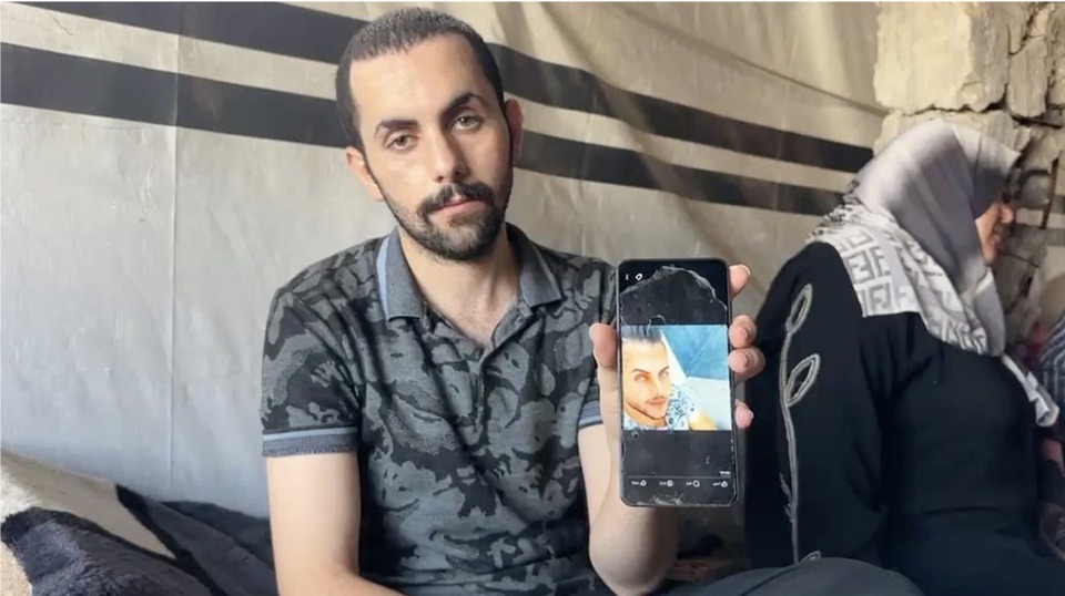 Hamada Al-Banna holds up a picture of himself before his year-long detention by Israeli forces. His family thought he was dead and held a funeral for him